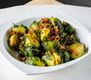 A bowl of brussels sprouts with bacon on top.