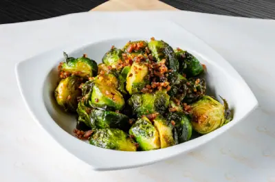 A bowl of brussels sprouts with bacon on top.