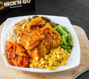 A bowl of food with chicken, corn and broccoli.