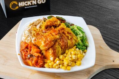 A bowl of food with chicken, corn and broccoli.