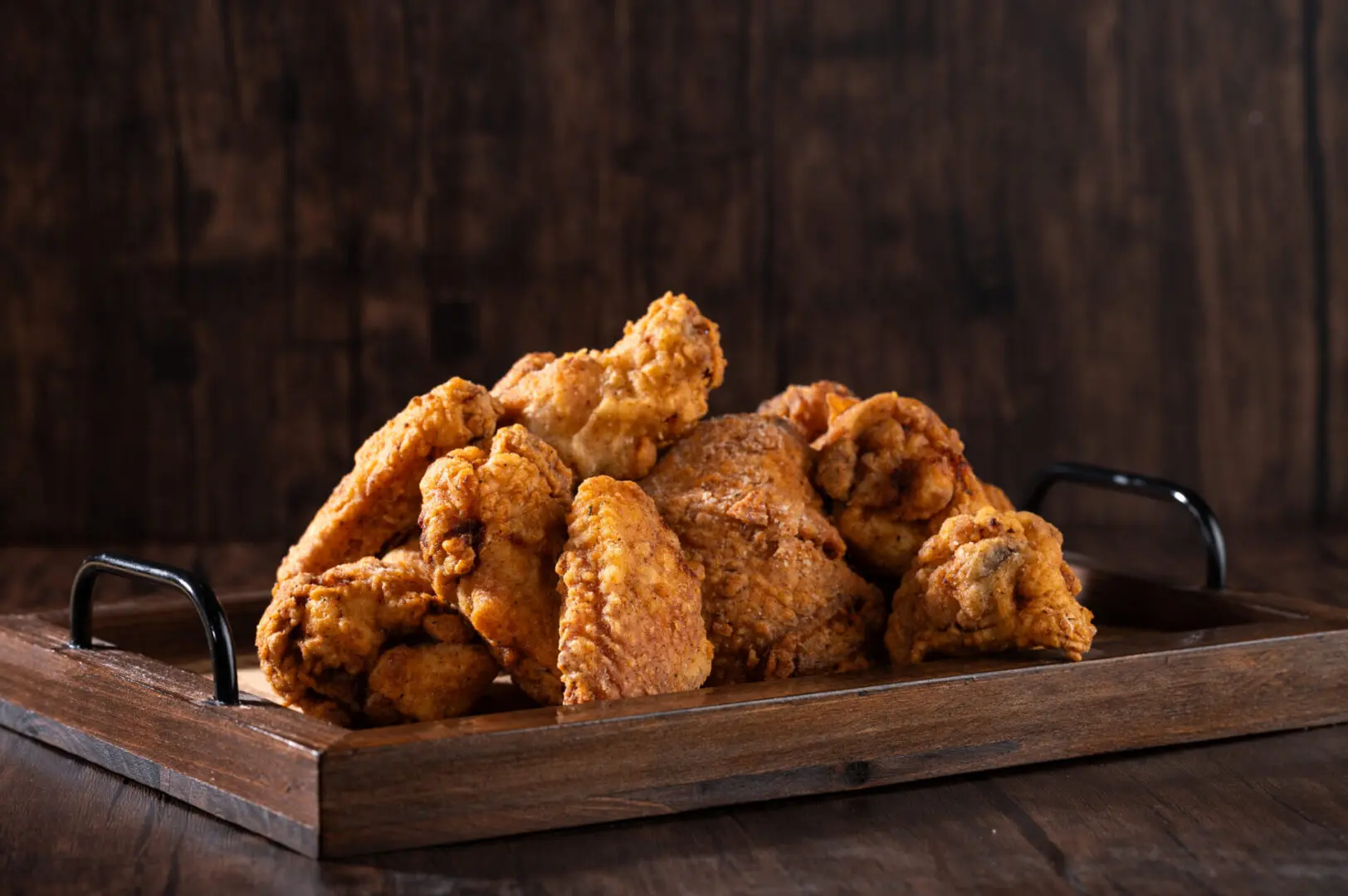 A wooden tray filled with lots of fried chicken.